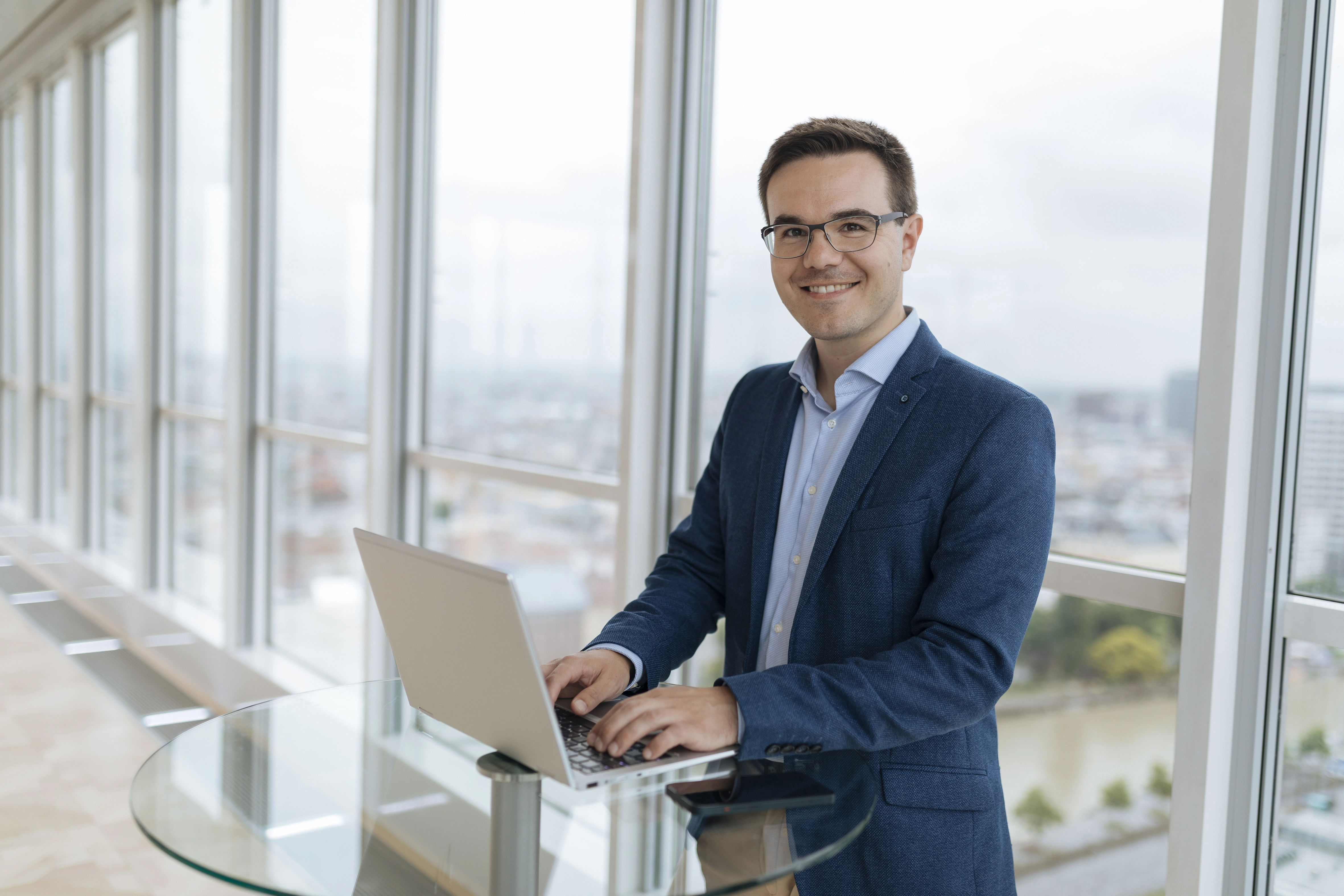 Mann auf Laptop arbeitend vor Fenstern