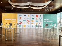 VIG HV 2024 Speisesaal; Stehtische vor Plakatwand