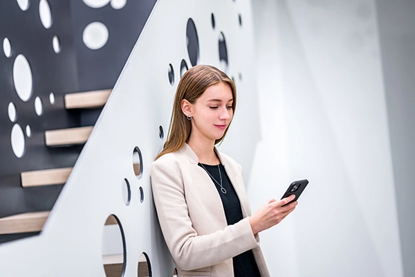 © Michael Kammeter Junge VIG Mitarbeiter:in lehnt an futuristischer Stiege und sieht auf ihr Handy