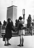 Schwarz-Weiß-Aufnahme: Zwei Mädchen stehen händehaltend vor dem Ringturm